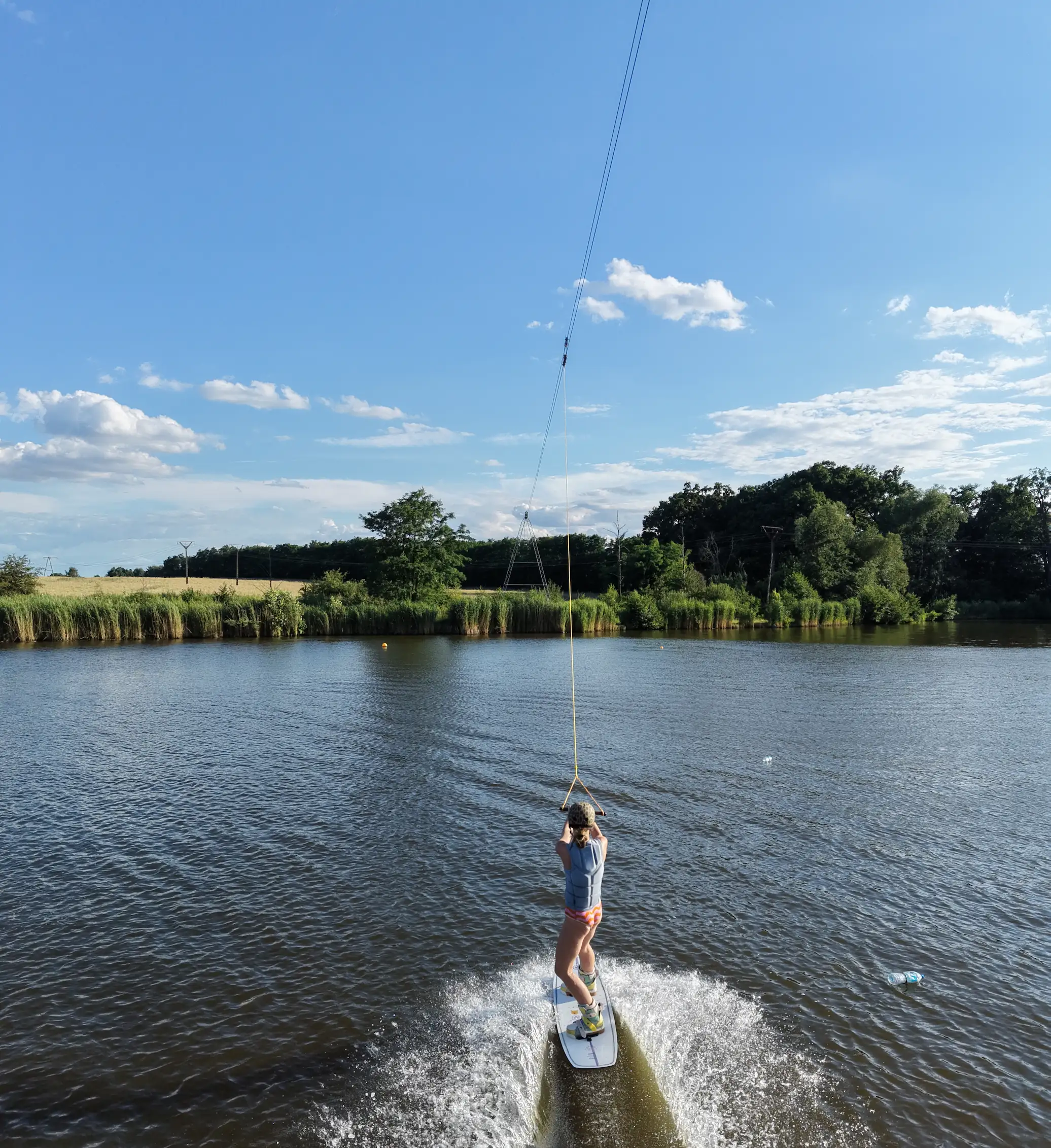 Osoba płynie na wakeboardzie za wyciągiem